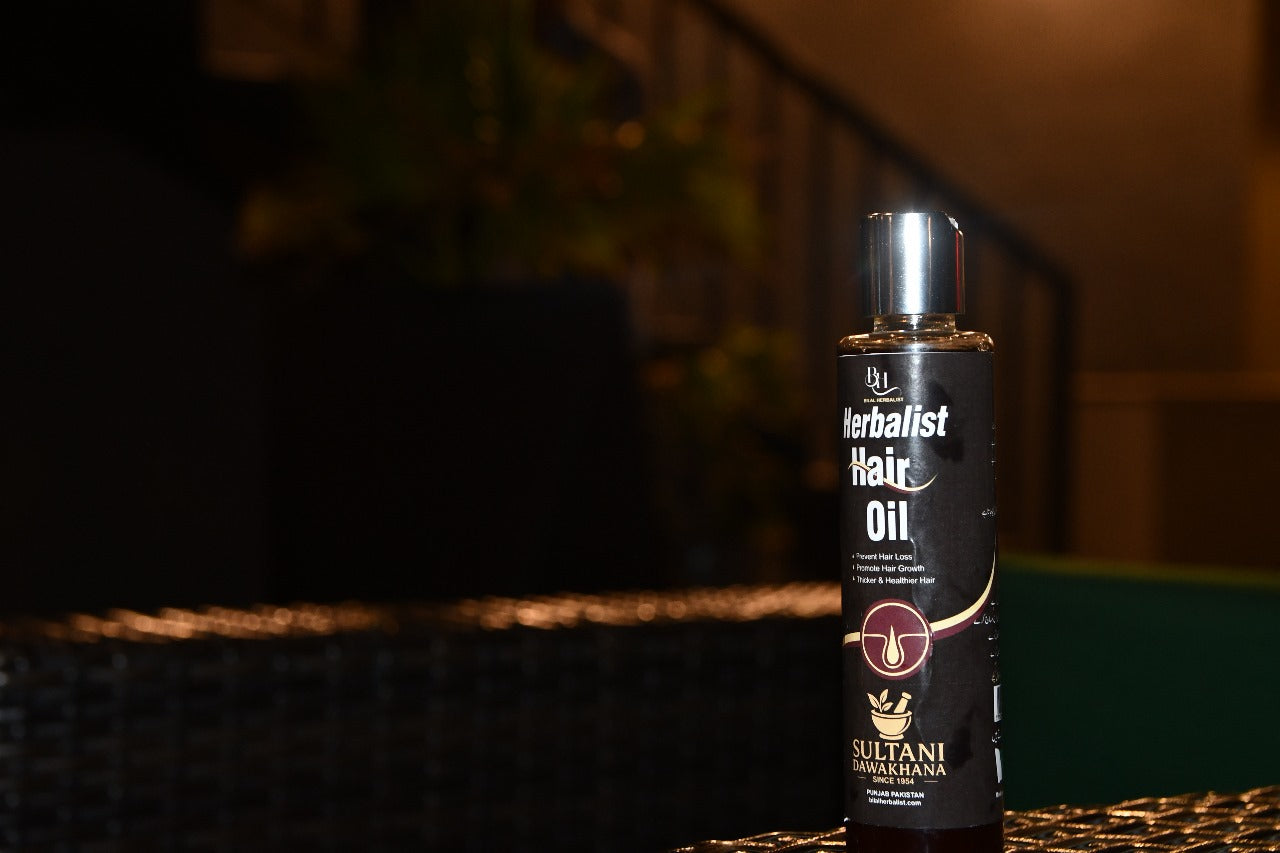 Bottle of Sultani Herbalist Hair Oil on a dark background