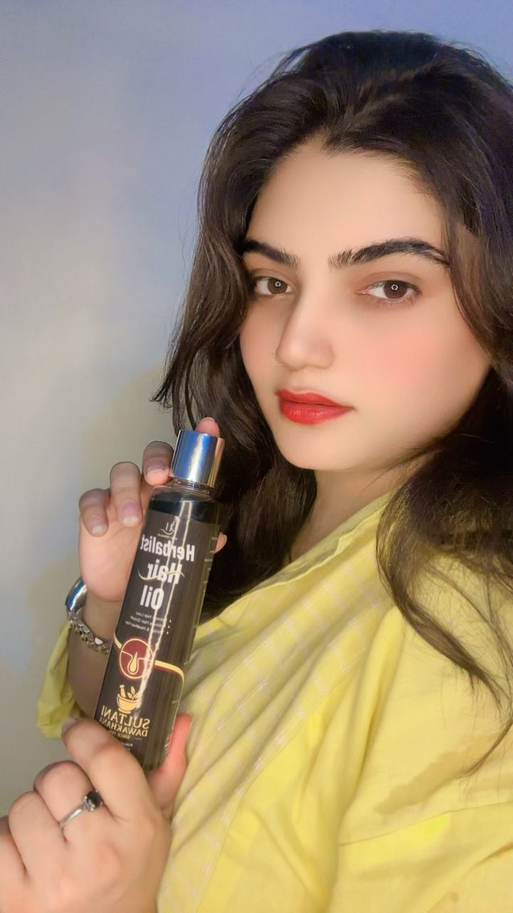 Woman holding a bottle of hair oil with a blurred background